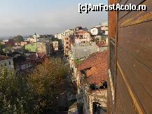 P18 [NOV-2012] Vedere laterală din cameră în cealaltă parte. Se vede acoperişul clădirii abandonate de alături, un minaret şi o cupolă de biserică cu cruce. 